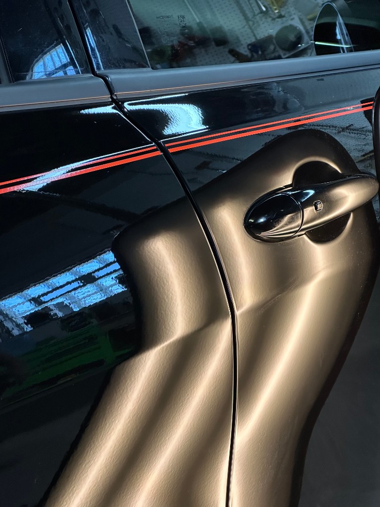 After PDR: same black door, dent removed under handle area, clean reflections