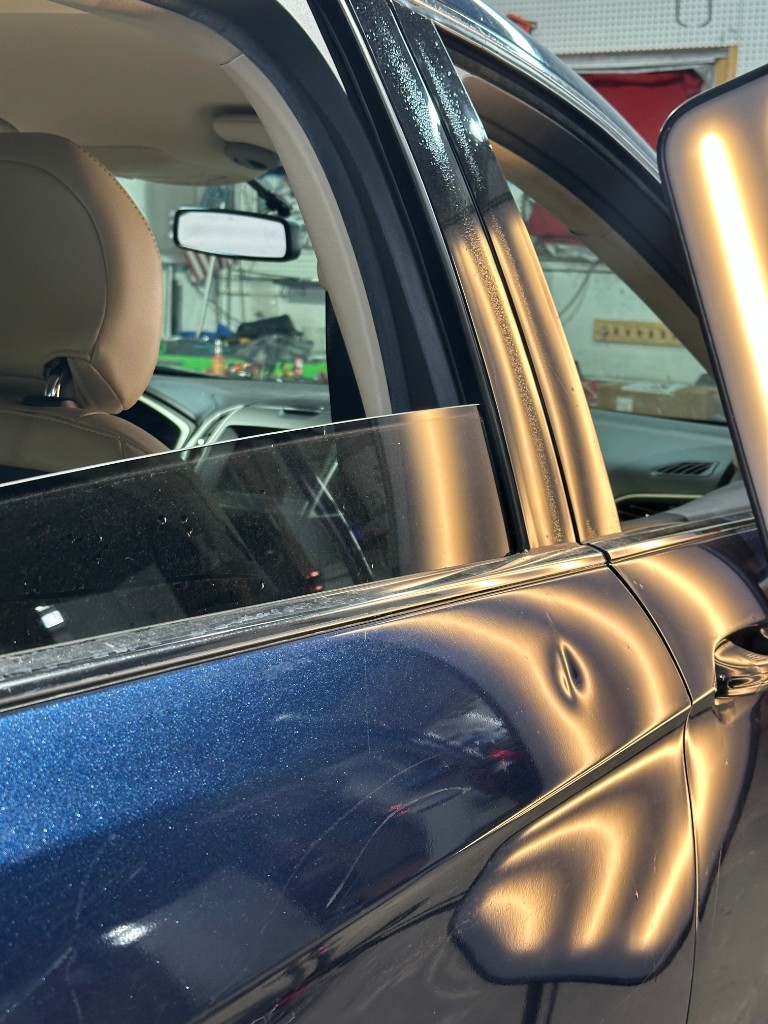 Before PDR: dark blue metallic car door with dent, technician light board reflection