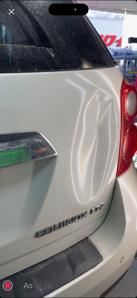 Before PDR: white Chevrolet Equinox LTZ rear liftgate with vertical creased dent